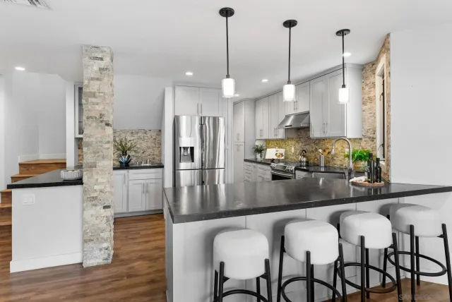 a kitchen with kitchen island granite countertop a table chairs stainless steel appliances and wooden floor