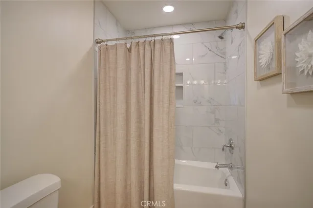 a bathroom with a shower curtain a toilet and a shower
