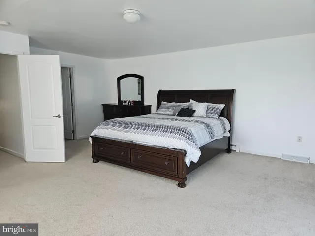 a spacious bedroom with a bed and a dresser