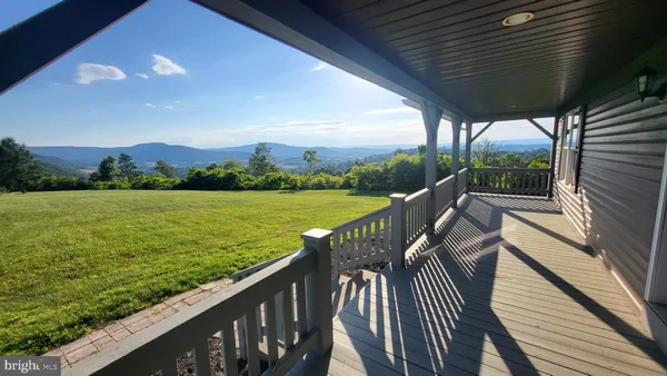 a view of a balcony with wooden floor and a garden