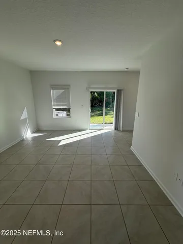 a view of an empty room with glass door and windows