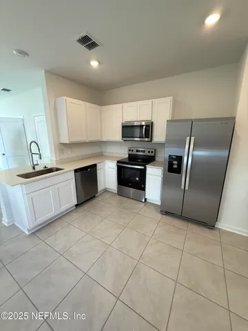 a kitchen with kitchen island granite countertop a stove top oven a sink a counter top space and cabinets
