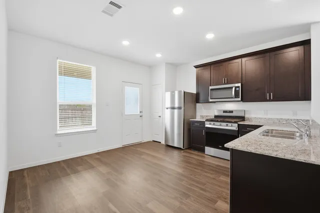 a kitchen with refrigerator a microwave a sink and cabinets