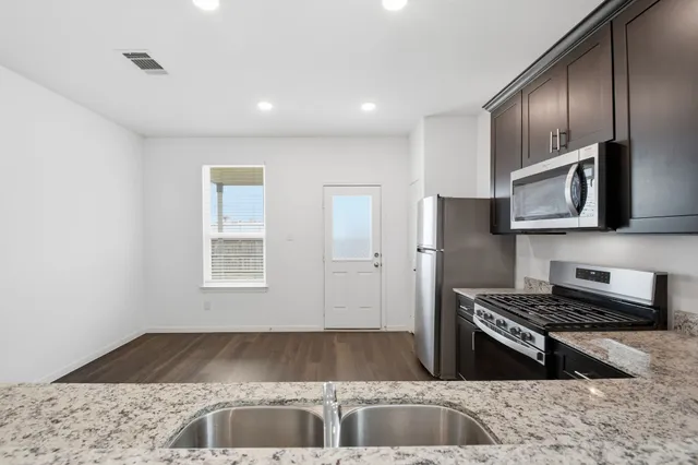 a kitchen with stainless steel appliances granite countertop a refrigerator and a sink