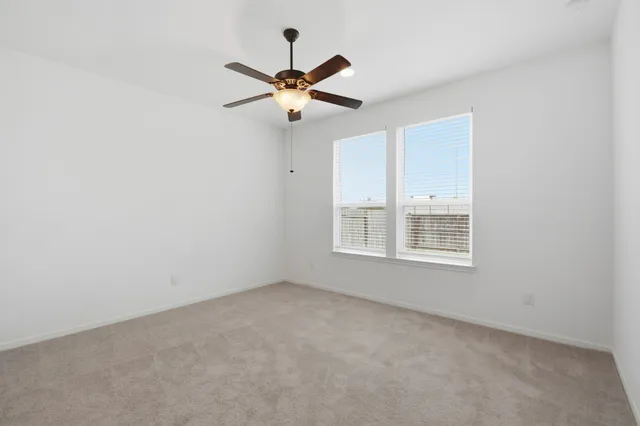 an empty room with windows and fan