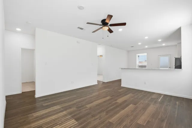 a view of empty room with wooden floor and ceiling fan
