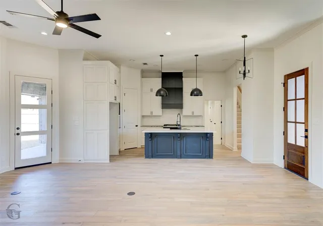 a large kitchen with stainless steel appliances kitchen island a large counter top and a refrigerator