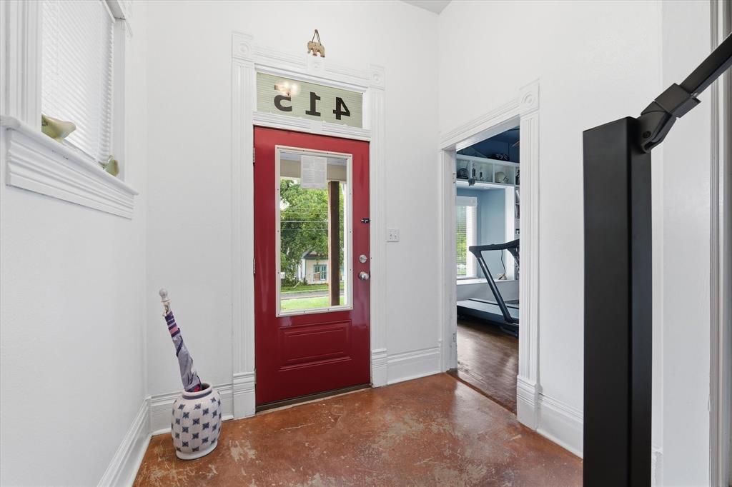 415 South Rice Street Hamilton, TX 76531 - Photo 4 of 28 Entryway featuring a red paneled door with glass insert, transom window, and a brown-toned concrete floor