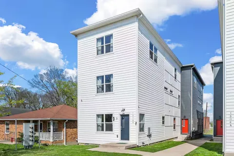 a view of a white house with a yard and potted plants