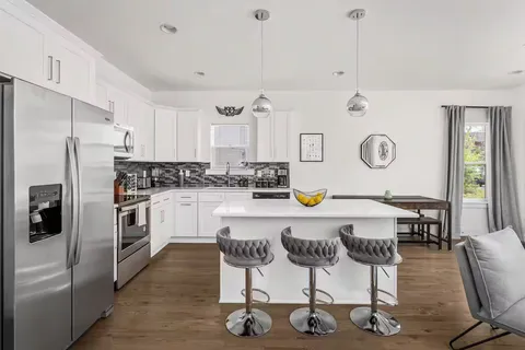 a kitchen with a refrigerator a stove a sink dishwasher with a dining table and chairs