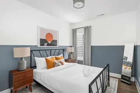 a bedroom with a bed and a lamp on dresser