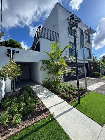 a front view of a house with a yard and potted plants