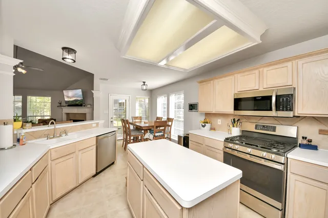 a kitchen with stainless steel appliances a sink a stove a refrigerator cabinets and a dining table