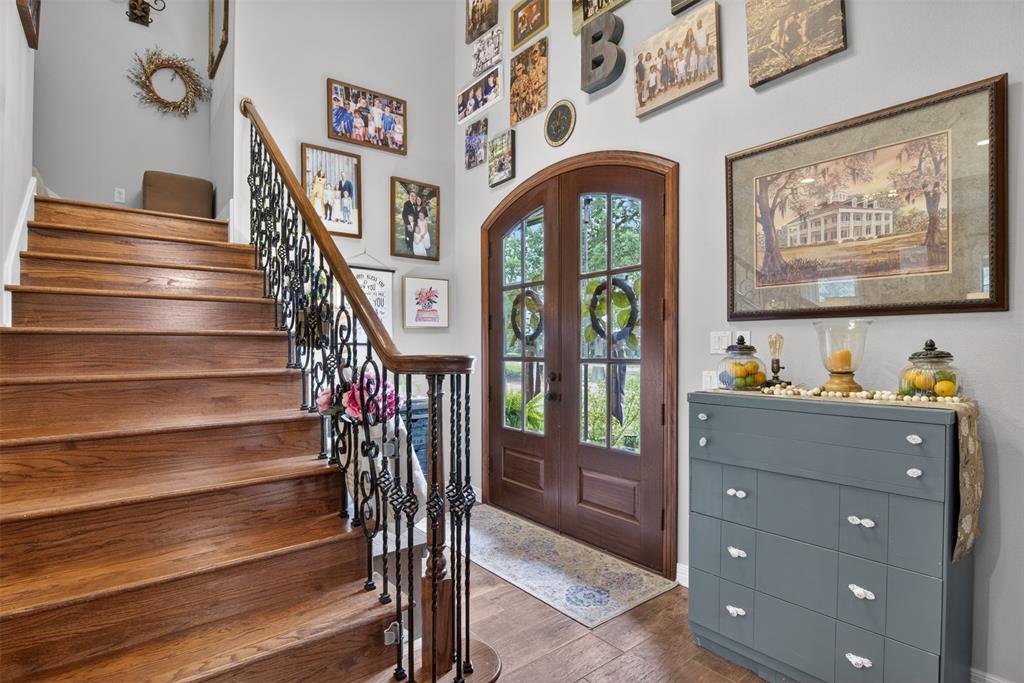 11868 Timber Ridge Drive Keithville, LA 71047 - Photo 5 of 37 Grand entryway featuring a double arched-top door with glass panels, wood-finish flooring, and a staircase with an ornamental metal railing and wood treads