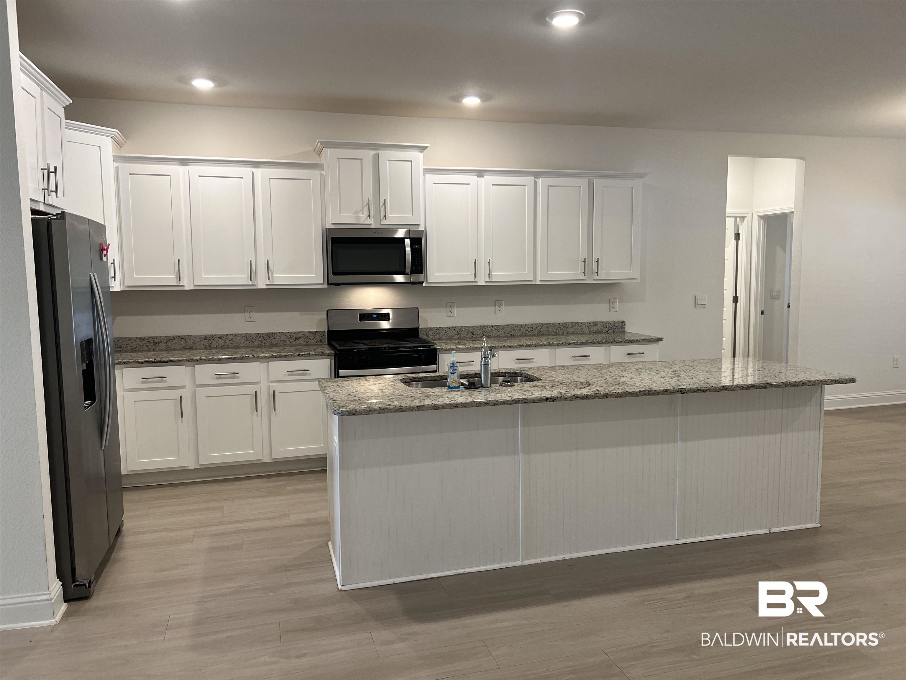 8855 Calverton Street Foley, AL 36535 - Photo 34 of 76 Kitchen with white cabinetry, stainless steel appliances, and a kitchen island with sink