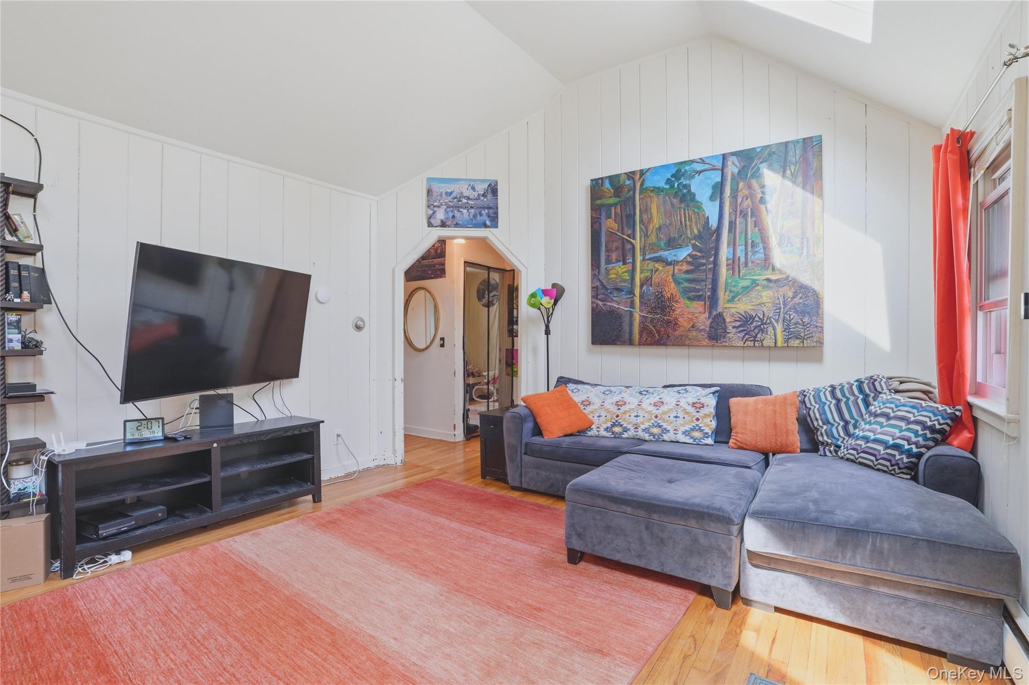 167 Highland Road Cold Spring, NY 10516 - Photo 8 of 22 Living area featuring hardwood floors, a vaulted ceiling with skylight, and a doorway with an arched frame