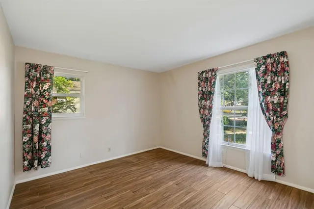 a view of an empty room with window and wooden floor