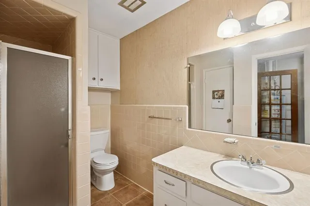 a bathroom with a toilet sink a mirror and shower
