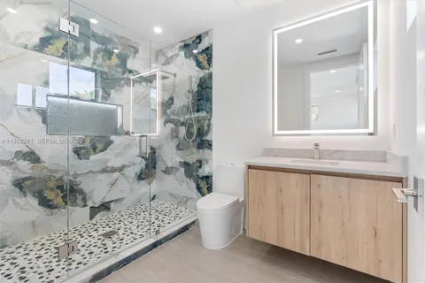 a bathroom with a granite countertop sink a toilet and shower
