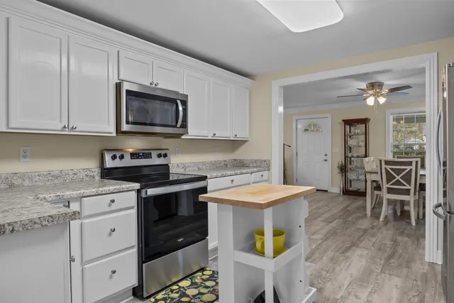 a kitchen with stainless steel appliances granite countertop a stove top oven a sink a microwave and a dining table