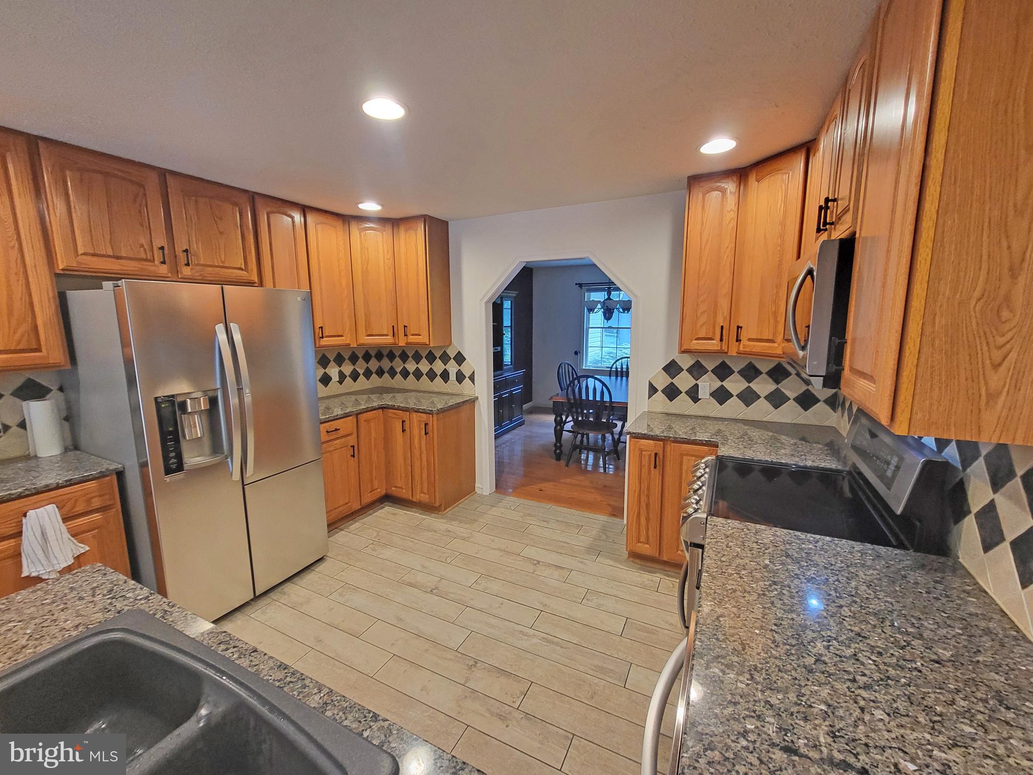 212 Walnut Dale Road Shippensburg, PA 17257 - Photo 16 of 56 a kitchen with stainless steel appliances granite countertop a refrigerator a stove and a sink with wooden floor