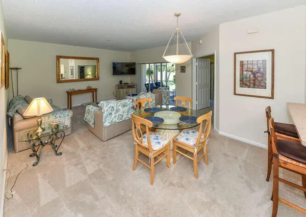 a kitchen with stainless steel appliances kitchen island a table chairs in it and white cabinets