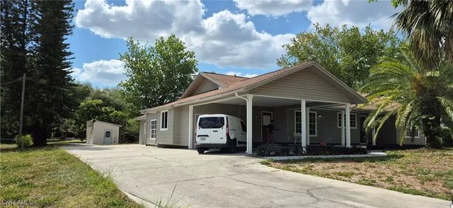 a view of a house with a yard and palm trees