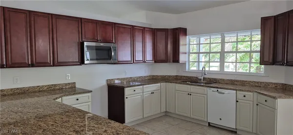 a kitchen with granite countertop wooden cabinets a sink and a window