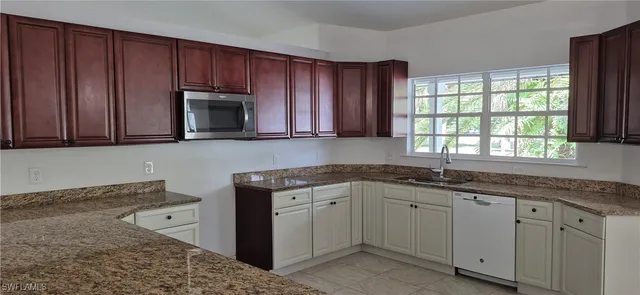 a kitchen with granite countertop wooden cabinets a sink and a window