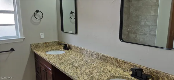 a bathroom with a granite countertop sink and a mirror