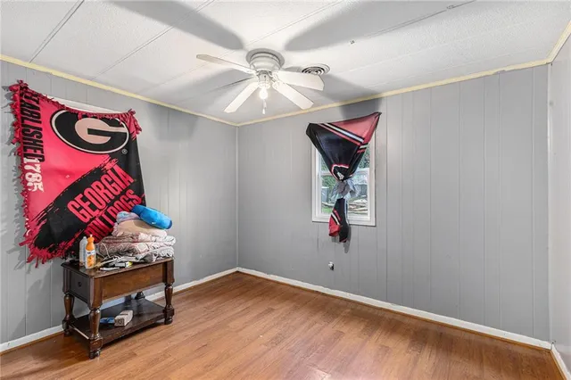an empty room with ceiling fan and wooden floor