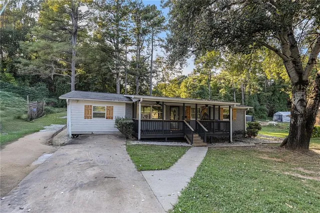 a view of a house with a yard and a large tree