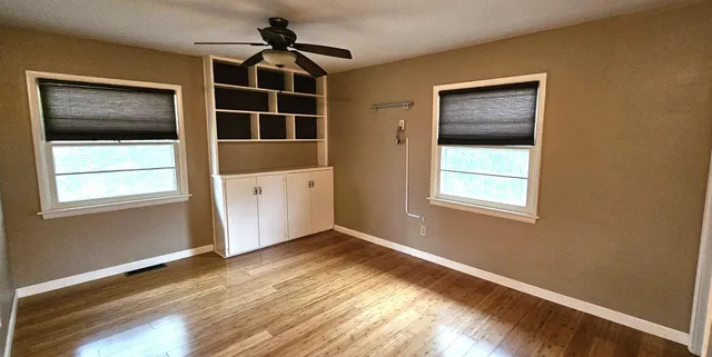 a view of an empty room with a window and wooden floor