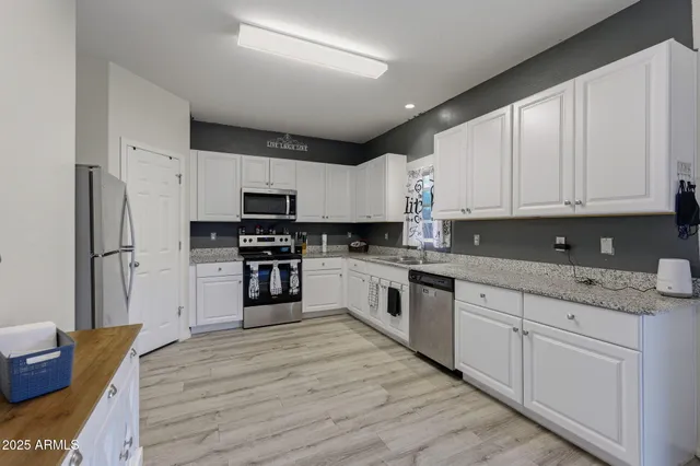 a kitchen with granite countertop a refrigerator sink and white cabinets