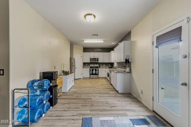 a kitchen with granite countertop a refrigerator sink and white cabinets