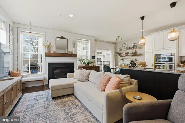 a living room with stainless steel appliances kitchen island granite countertop a couch and white cabinets