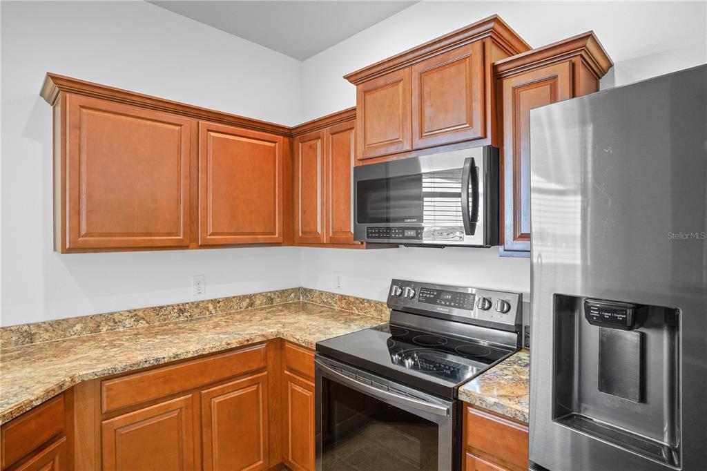 222 Blackstone Creek Road Groveland, FL 34736 - Photo 15 of 49 a kitchen with granite countertop stainless steel appliances and wooden cabinets