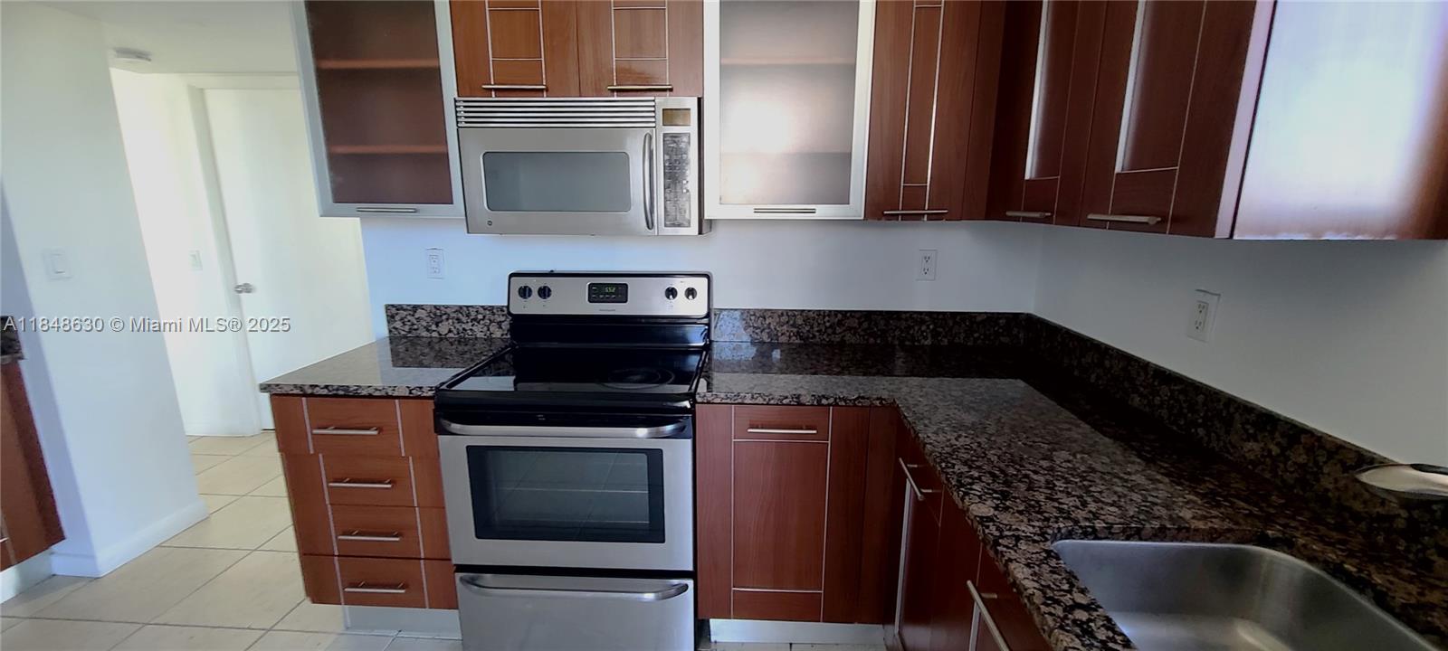 3300 Northeast 191st Street, Unit 1207 Aventura, FL 33180 - Photo 14 of 33 a kitchen with granite countertop a stove top oven cabinetry and garage