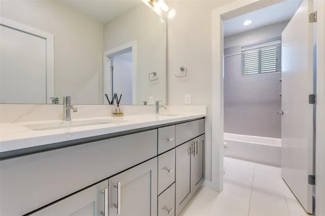 a bathroom with a double vanity sink a mirror and a bathtub