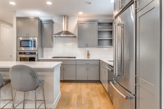 a kitchen with stainless steel appliances granite countertop a refrigerator and a stove top oven