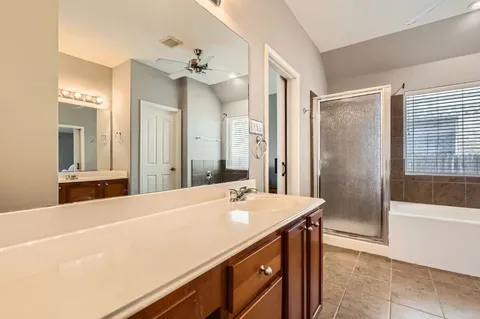 a bathroom with a sink double vanity granite tub shower and a mirror