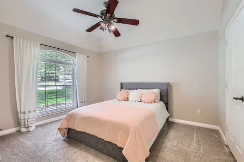 a bedroom with a bed ceiling fan and a window