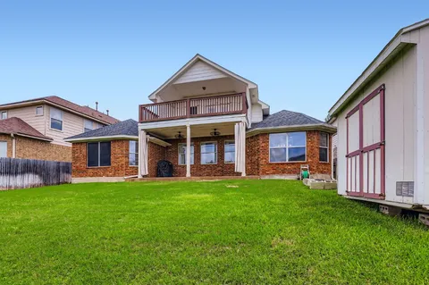 a view of a brick house with a big yard and large trees