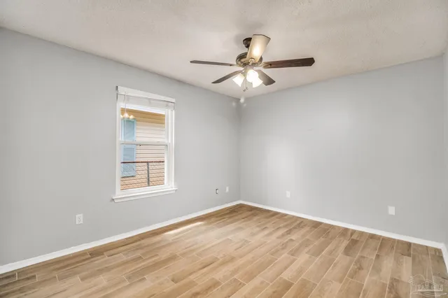 an empty room with wooden floor fan and windows