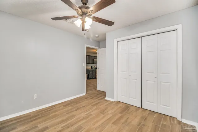 an empty room with closet and a ceiling fan