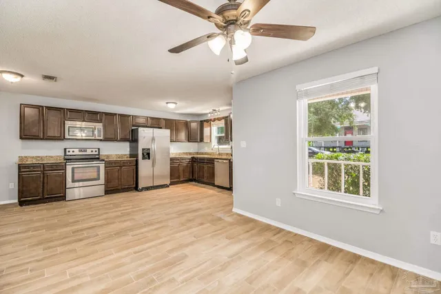 a kitchen with stainless steel appliances granite countertop a stove top oven a refrigerator cabinets and a window