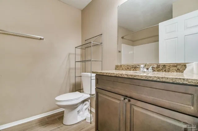a bathroom with a granite countertop toilet sink and mirror