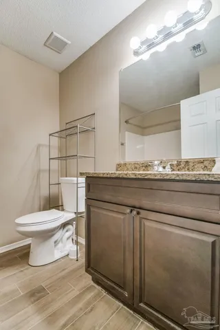 a bathroom with a granite countertop toilet sink and mirror