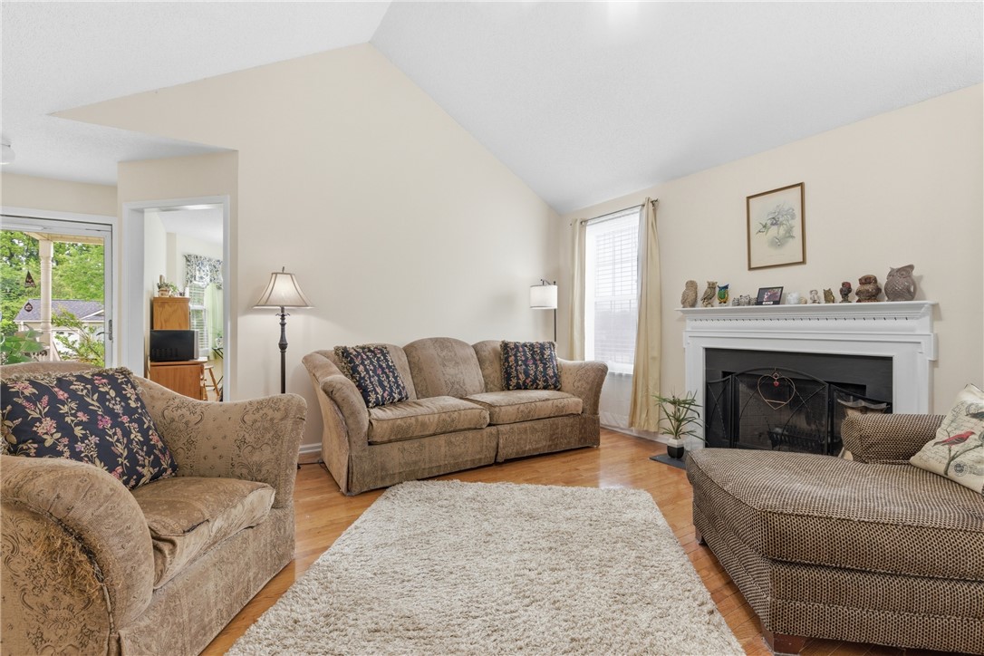 128 Kelly Lane Easley, SC 29642 - Photo 13 of 23 A welcoming living room features a classic fireplace and lustrous hardwood flooring beneath a soaring vaulted ceiling.