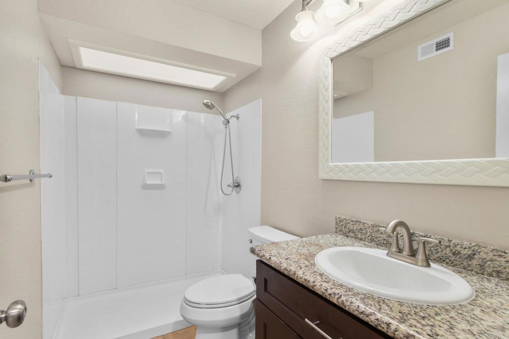 5667 Adobe Falls Road, Unit C San Diego, CA 92120 - Photo 30 of 40 a bathroom with a granite countertop sink toilet and shower